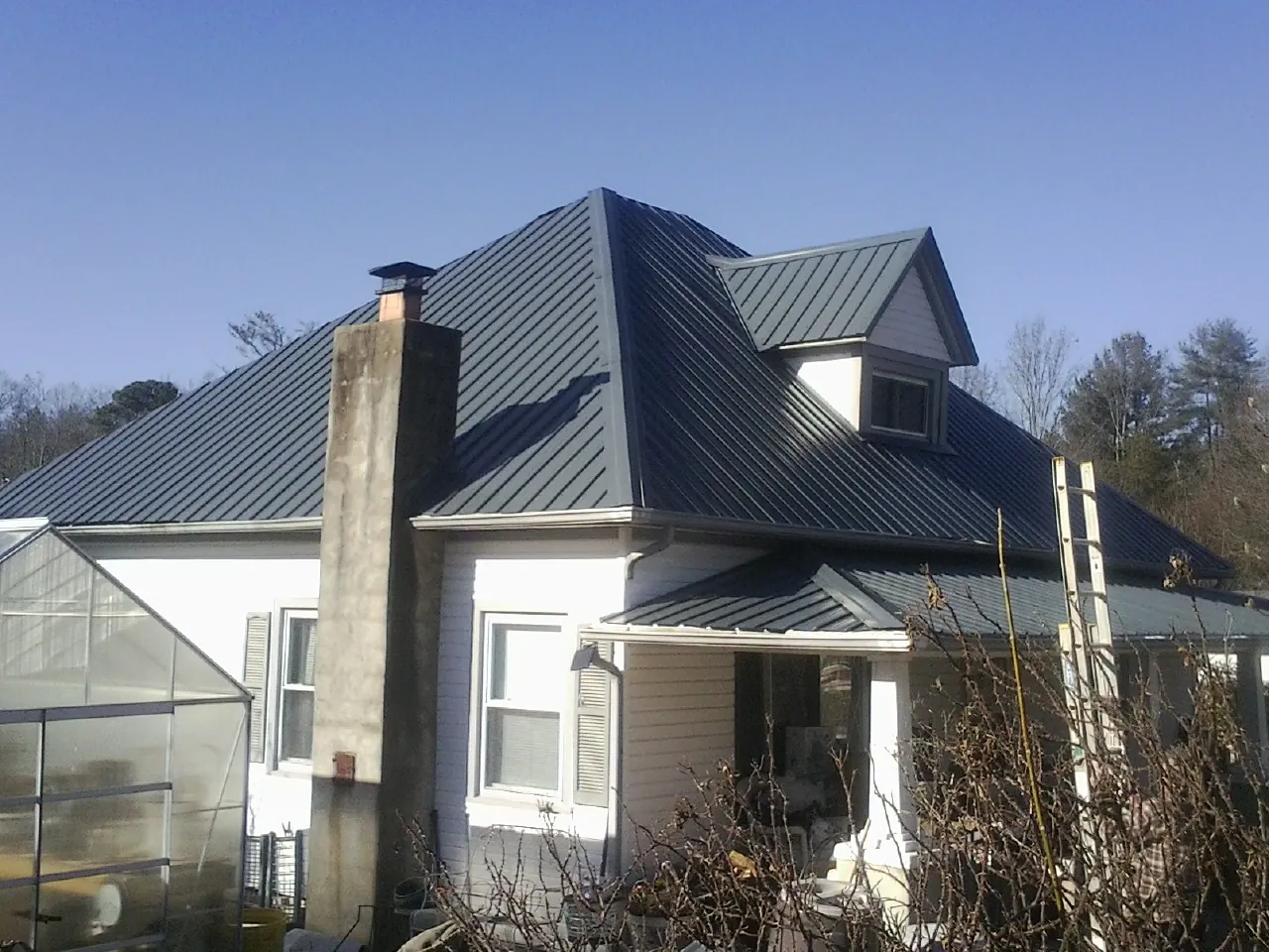 Dark blue standing seam metal roof on a white farmhouse with dormer — Slate & Tile Roof Repair by Roofing Brothers in Beverly Shores
