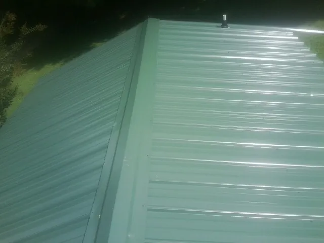 New green metal panels meeting at the ridge of a roof — Flat Roof Repair work by our crew in Beverly Shores