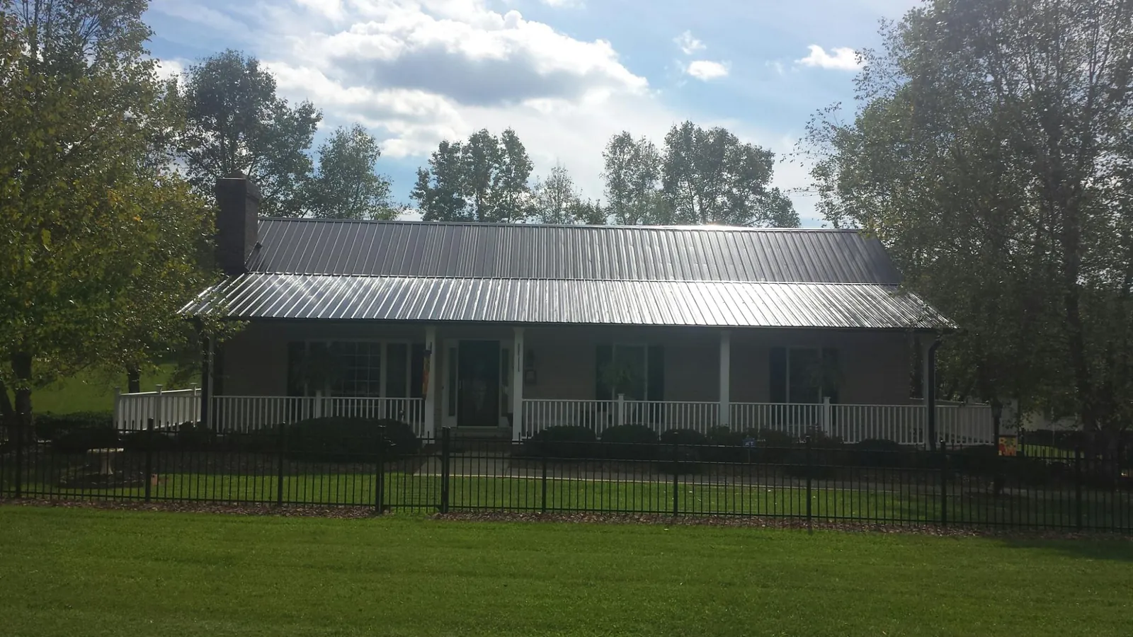Gray metal roof on a brick ranch with a full width front porch — Gutter Guard Installation work by our crew in Beverly Shores