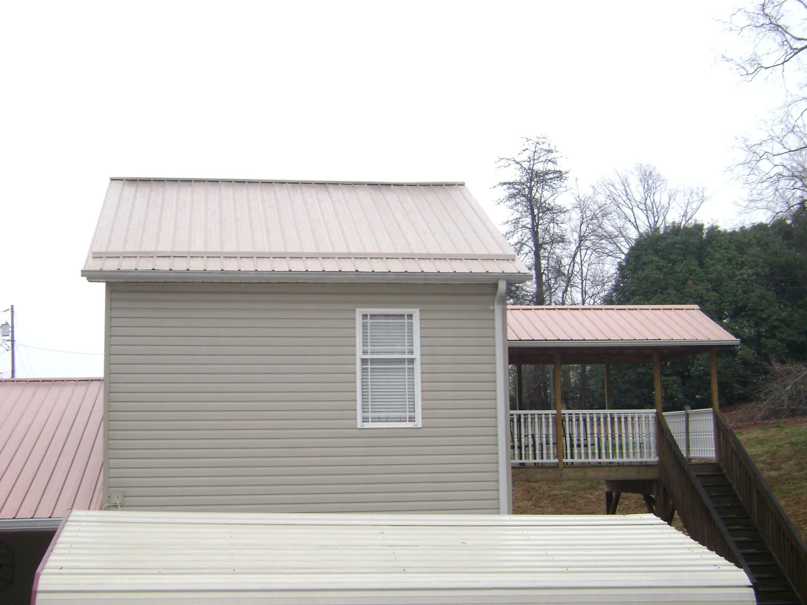 Tan metal roofs on a two story addition and attached porch, from a Roof Replacement job in Beverly Shores