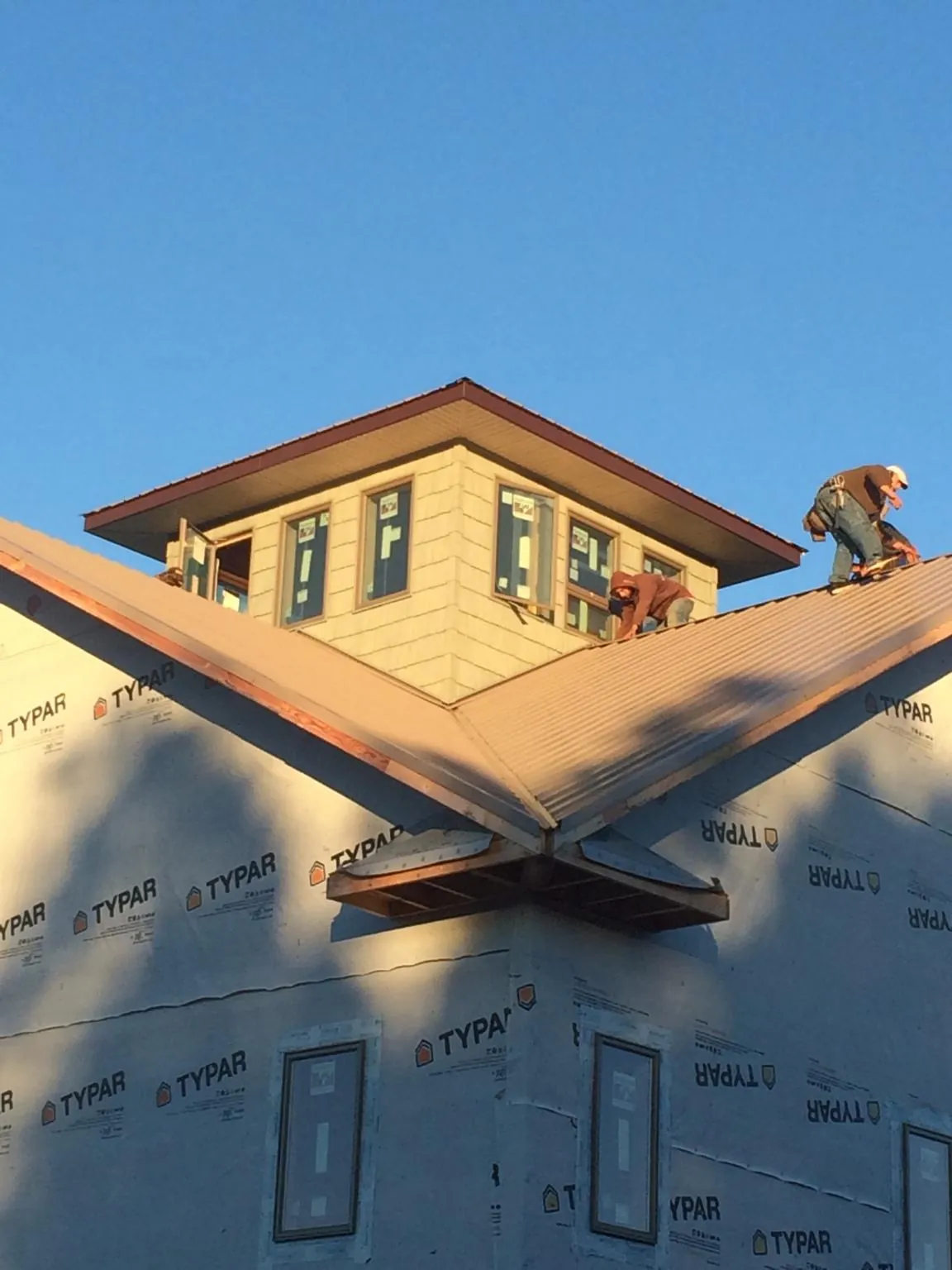 Roofers working around a rooftop cupola on a new metal roof at sunset — Roof Waterproofing in Beverly Shores by Roofing Brothers